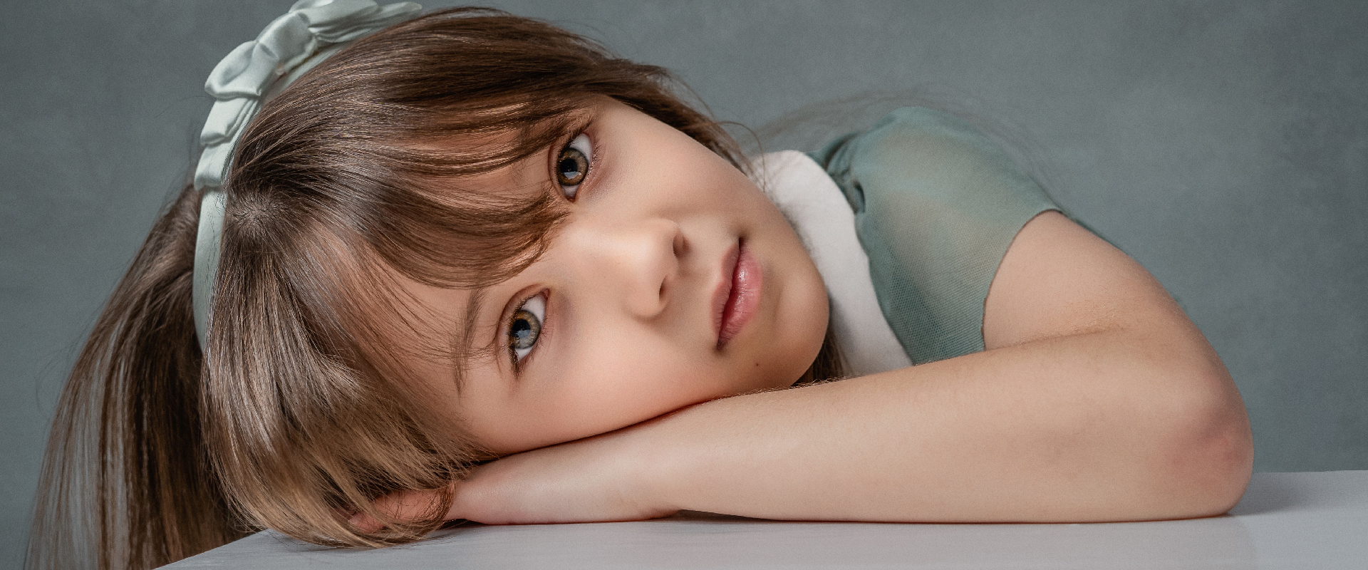 Retrato infantil de niña recostada sobre una mesa